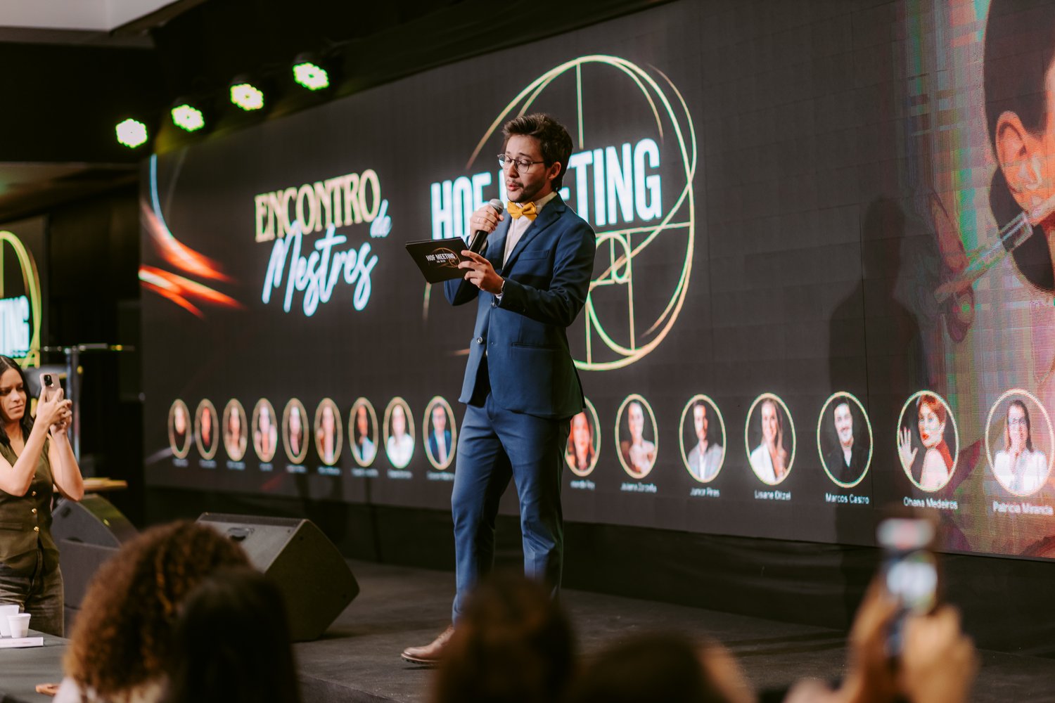 Dr. Gustavo Martins no palco do HOF Meeting conduzindo o evento